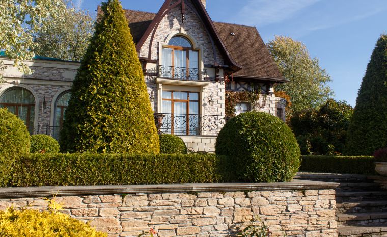 A spacious stone residence with a decorative stone wall and vibrant hedges, emphasizing its attractive curb appeal in Guilford, CT.