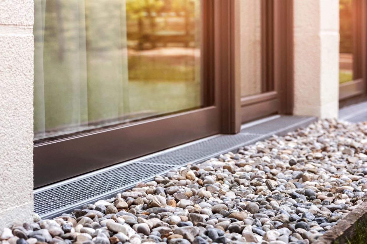 A window embedded in a stone wall, next to a stone walkway, illustrates drainage solutions in Mystic, CT.