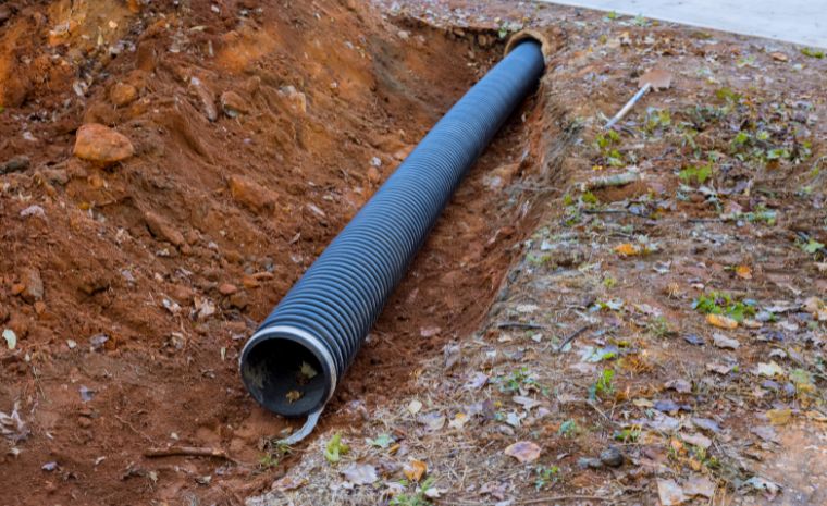 A pipe is situated in the ground, demonstrating drainage solutions in Old Saybrook, CT, particularly French drains.