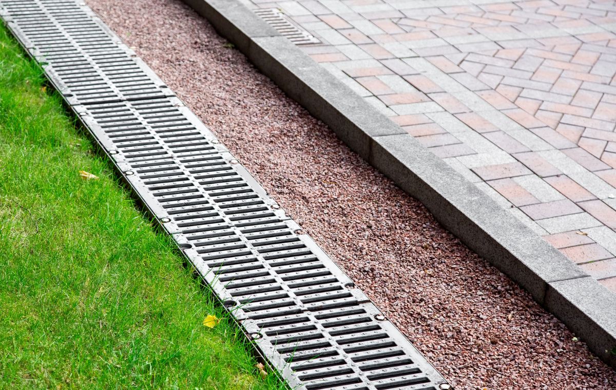 A metal grate placed next to a brick walkway, intended for efficient drainage in Old Saybrook, CT.