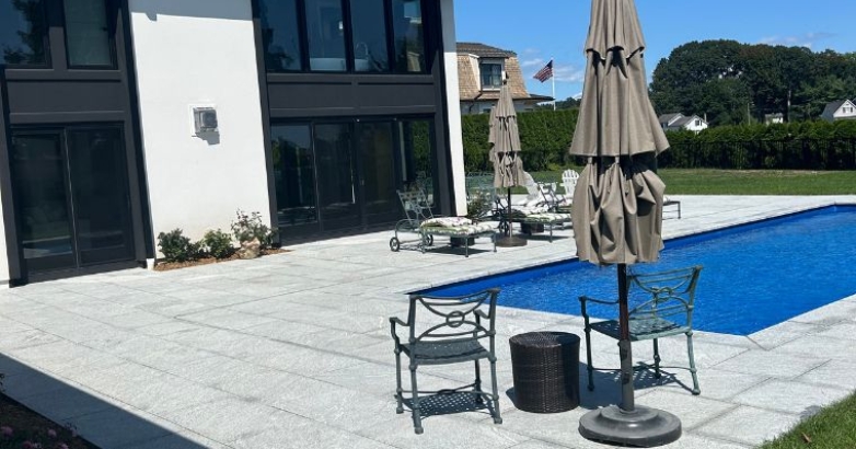 A pool surrounded by a patio umbrella and chairs, showcasing a family-friendly outdoor area for relaxation and enjoyment.