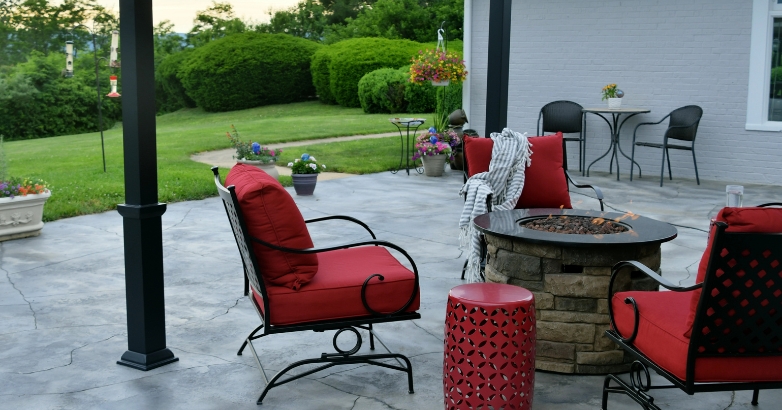 A charming patio scene with red chairs and a fire pit, representing popular ideas for backyard outdoor spaces.