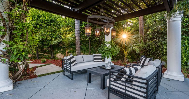 Luxury outdoor patio in Connecticut with modern black furniture, hanging lanterns, and lush greenery at sunset.