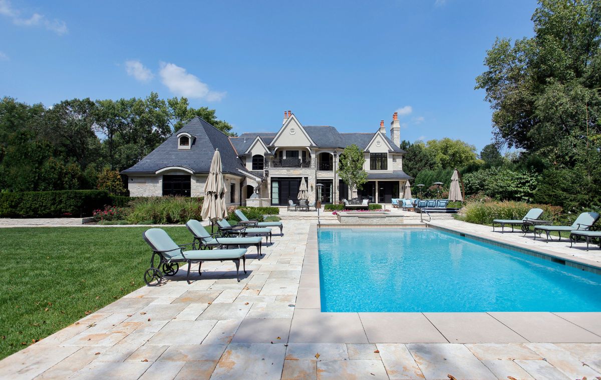 A large house in Chester, CT, featuring a pool and lawn chairs, highlighting the masonry craftsmanship of a local construction company.