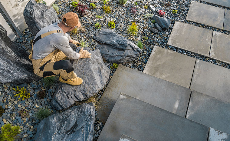 A man constructs a decorative stone patio for a masonry company in Stonington, CT, showcasing skilled craftsmanship.