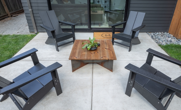Outdoor patio with four chairs and a table, showcasing concrete work by a contractor in Old Saybrook, CT.
