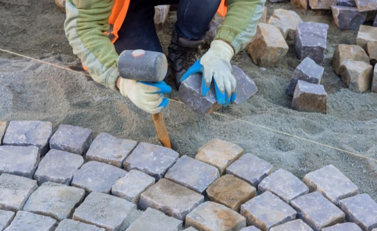 A contractor lays bricks on a walkway in a backyard, showcasing a veteran-owned business in Westport, CT.