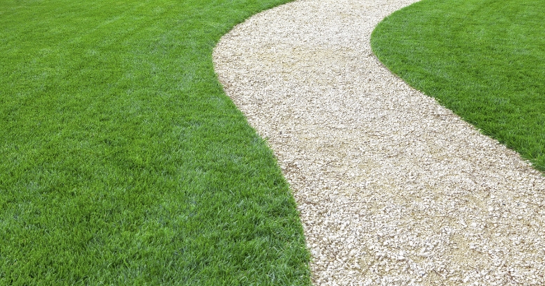 A curved gravel pathway bordered by grass, showcasing a front walkway idea for landscaping design.