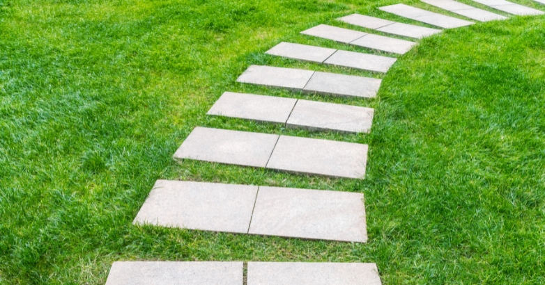 A grassy pathway featuring stone steps, illustrating a front walkway idea with stepping stones.