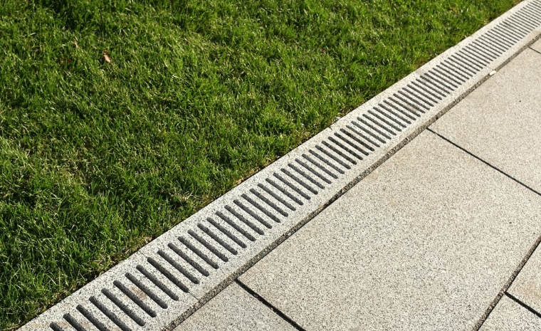 Grassy area featuring a central drain, highlighting drainage solutions by a concrete sidewalk contractor in Branford, CT.