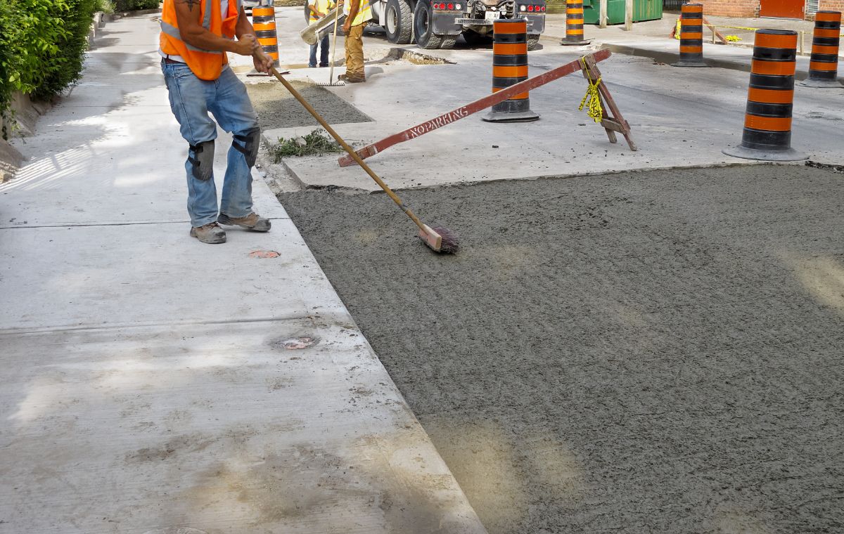 A concrete contractor uses a brush to lay concrete for a sidewalk in Essex, CT.