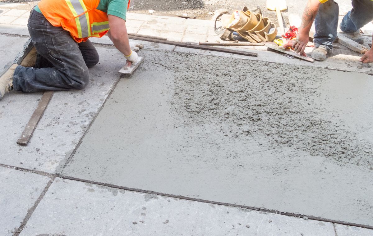 A man working on a sidewalk, finishing of a newly poured concrete surface as part of his role as a contractor in Fairfield, CT.