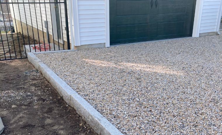 Gravel driveway leading to a garage door, featuring low-maintenance cobblestone edging in Chester, CT.