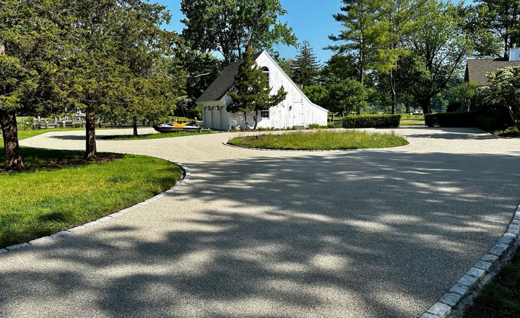 A white house is framed by a circular cobblestone driveway, showcasing increased value in Westport, CT.