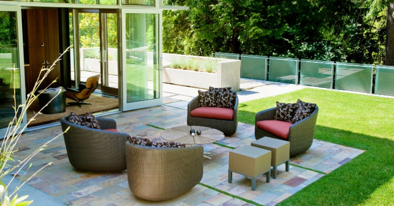 A stylish patio featuring elegant furniture and a glass door, showcasing luxury outdoor living space ideas.