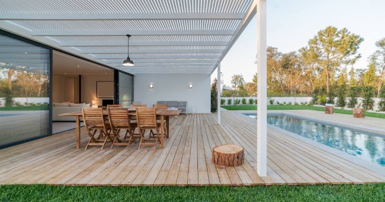A modern house featuring a pool and wooden deck, showcasing luxury patio ideas with seamless transitions.