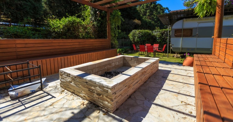 A sunken fire pit in a backyard, surrounded by built-in seating, showcasing luxury patio design ideas.
