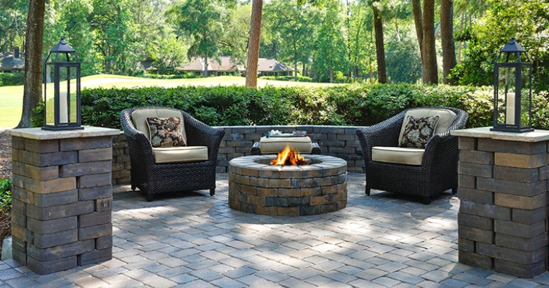 A cozy stone patio featuring a fire pit surrounded by comfortable chairs, ideal for outdoor lounging and gatherings.