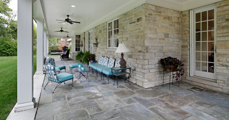 A cozy stone patio adorned with blue chairs and a ceiling fan, highlighting effective outdoor planning tips.