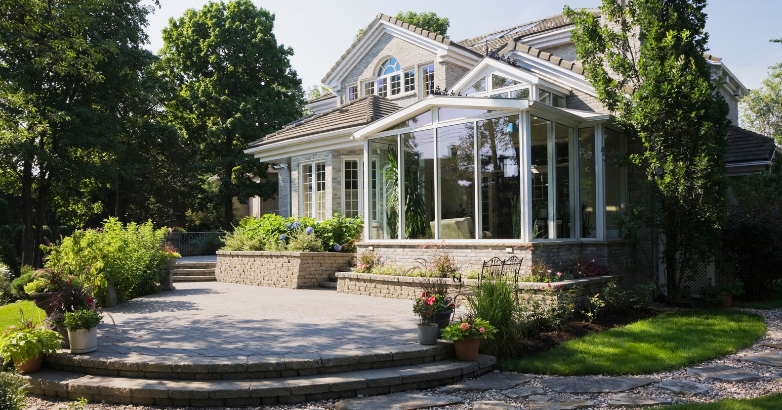 A home featuring a spacious stone patio and a large glass door, showcasing traditional garden patio design ideas.