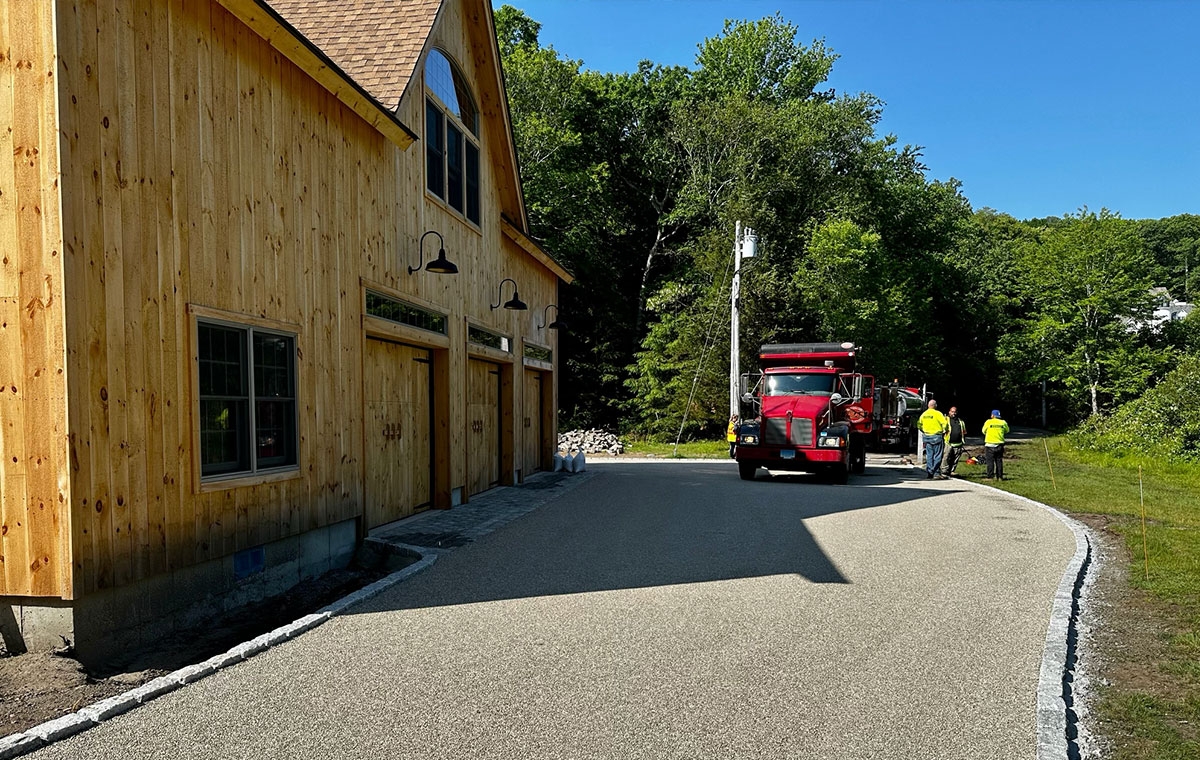 A man is installing cobblestone edging on a driveway next to a barn in Clinton, CT.