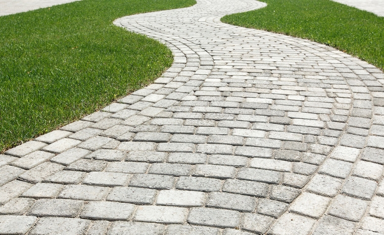 Custom-designed cobblestone pathway set in a grassy area, located in Greenwich, CT, inviting exploration.