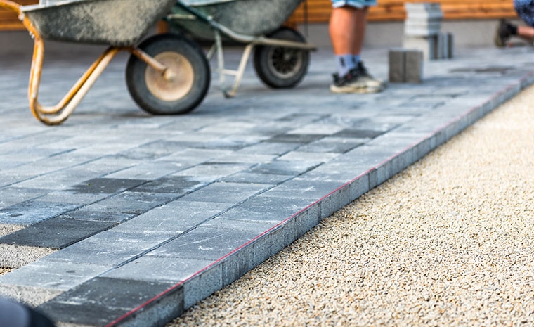 A man installs bricks on a walkway in Madison, CT, showcasing expert craftsmanship in paver installation.