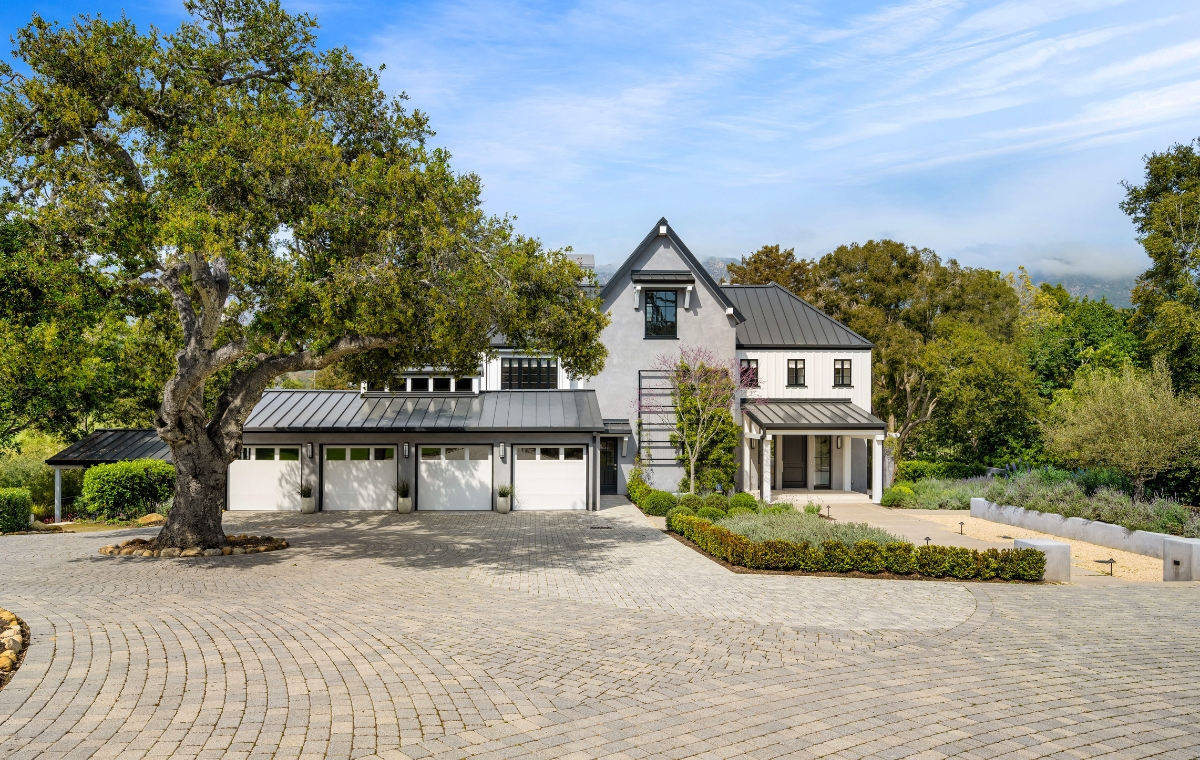 A prominent home with a driveway and trees, showcasing a paver walkway in Westport, CT.