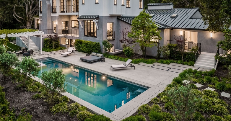 A luxury home featuring a pool surrounded by elegant landscaping, illustrating ideal outdoor living design.