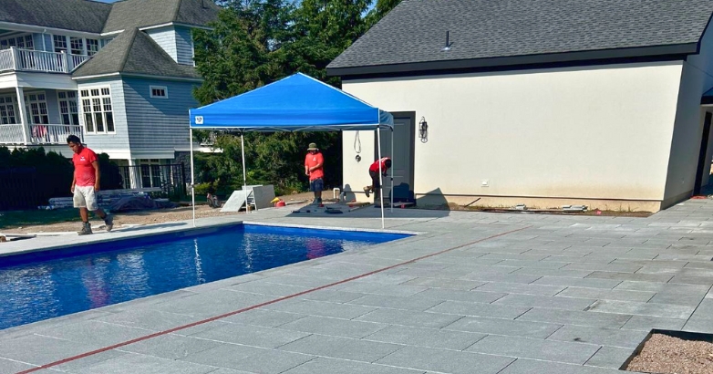A backyard scene with a pool under construction and a blue tent, emphasizing the pool deck building phase.
