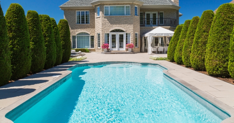 A spacious house with a pool and patio, showcasing granite as a choice for an elegant pool deck.