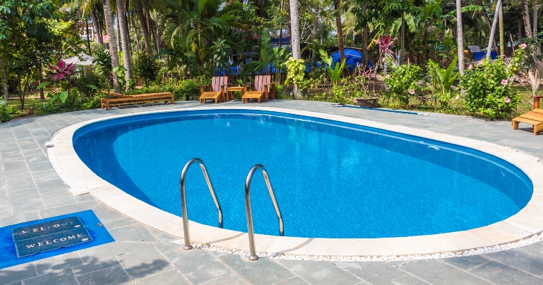 A swimming pool with blue tiles and chairs, serving as a visual reference for selecting the right stone for pool decks.