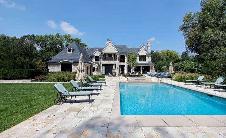 A spacious house with a pool and lawn chairs, surrounded by top-grade stone patios in Clinton, CT.