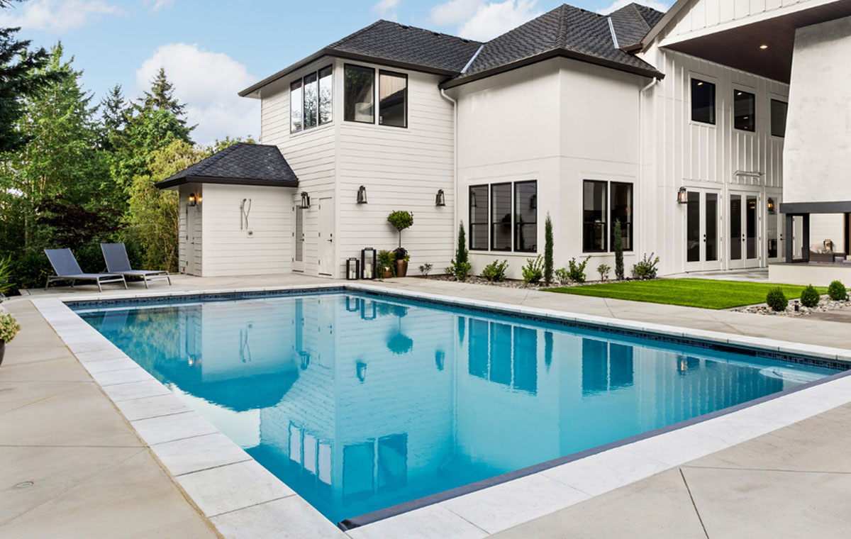 A large white residence with a pool and stone patio area, set in Mystic, Connecticut.