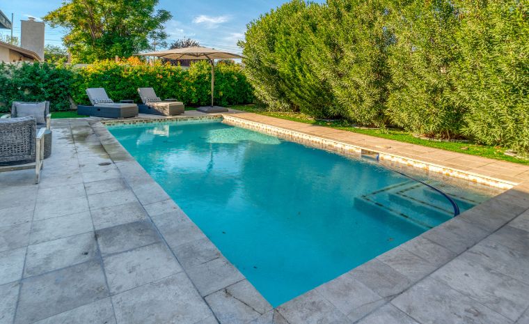A backyard featuring a pool surrounded by patio furniture, showcasing custom stone designs in Westport, CT.