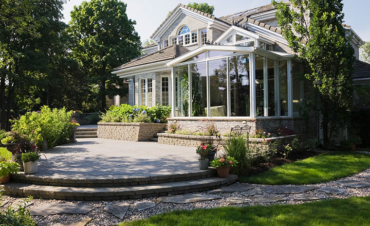 A house with an expansive patio and stone pathway, representing landscape design in Chester, CT.