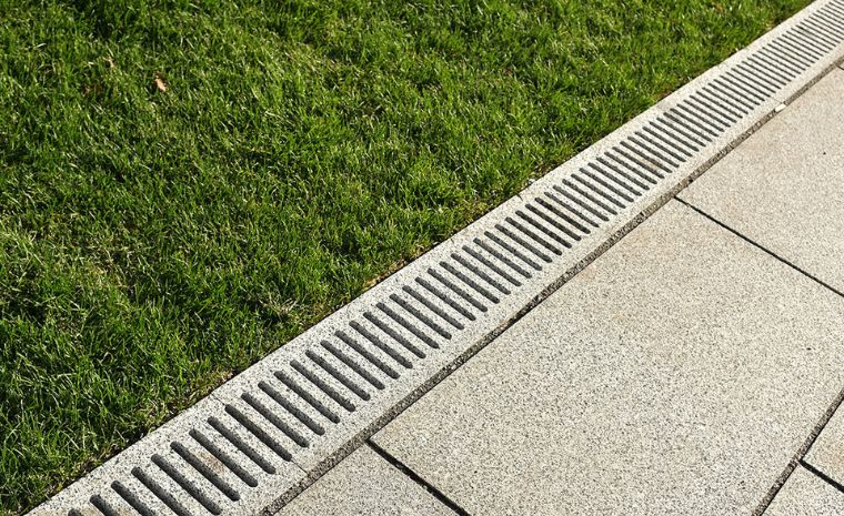 A grassy landscape with a drain at the center, illustrating drainage solutions in Clinton, CT's landscape design.