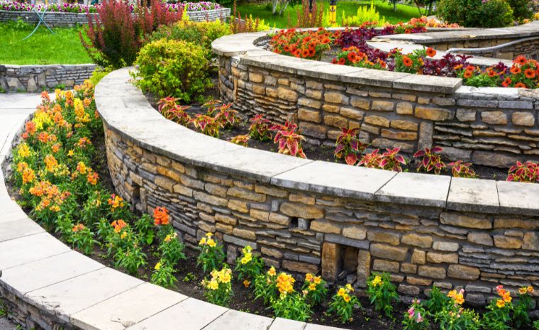 A stone wall adorned with vibrant flowers and plants, showcasing hardscape integration in a landscape design in Essex, CT.