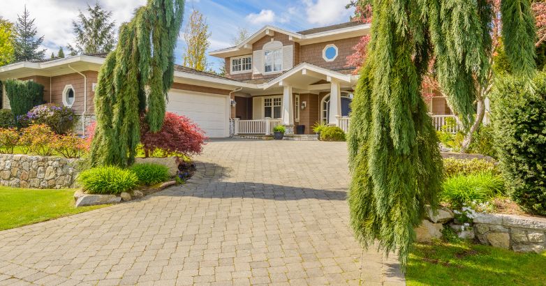 Suburban home with a wide paver driveway surrounded by landscaping—illustrating common residential use of paving materials