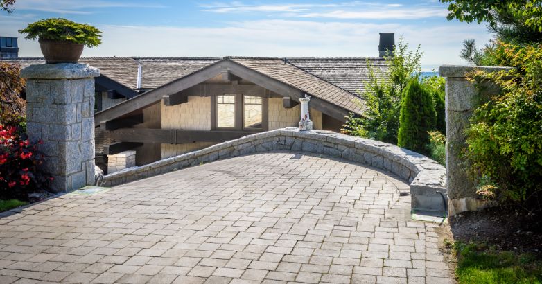 Curved driveway with stone pavers leading to a home, showcasing low-maintenance hardscaping design