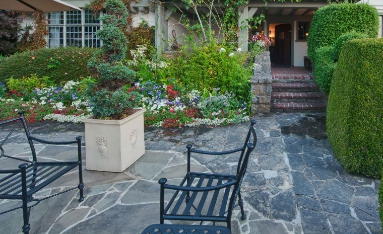A patio with a table and chairs in front of a house, highlighting a custom flagstone design in Branford, CT.
