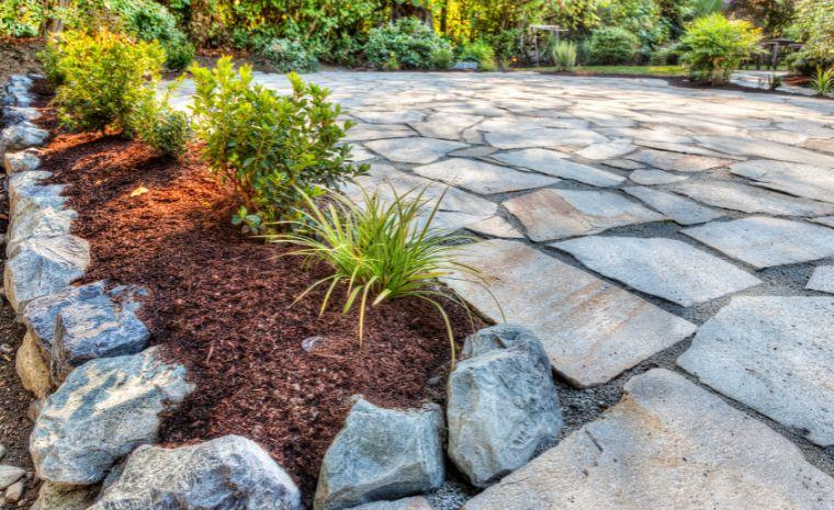 Flagstone patio with natural stone finish, decorative edging, and landscaped garden border