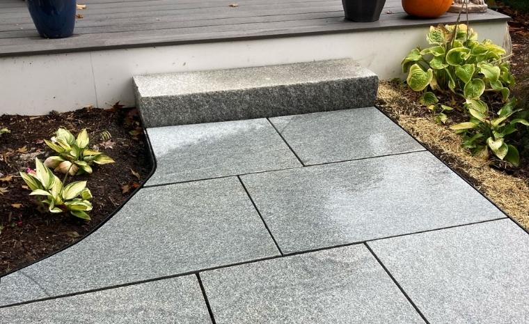A well-designed walkway with grey granite steps and a potted plant, highlighting the craftsmanship of a Clinton, CT contractor.
