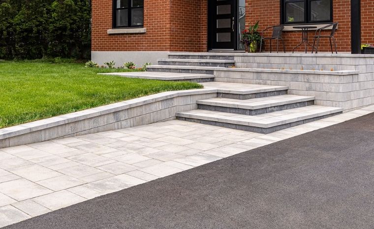 A brick patio with steps ascending to a house, representing the craftsmanship of a front walkway contractor in Madison, CT.