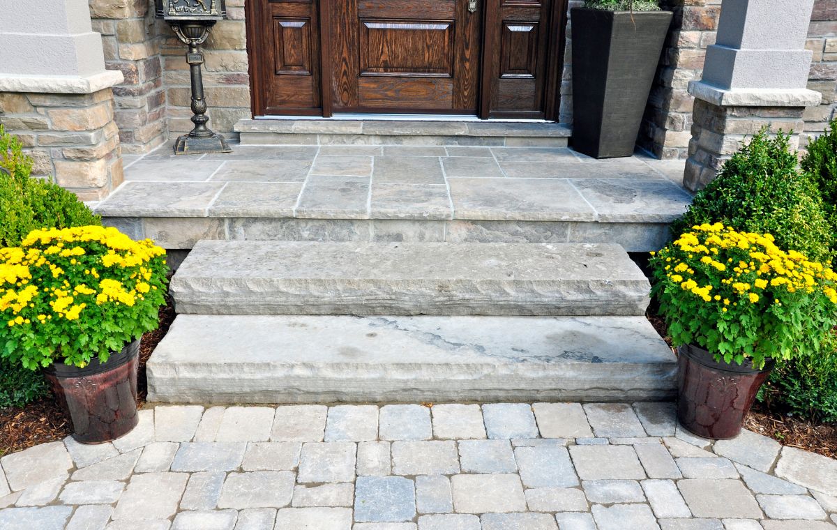 A welcoming front door surrounded by flowers, leading to a stone path, showcasing a Westport CT walkway contractor's work.