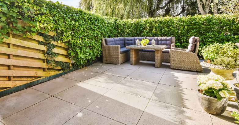 A modern outdoor patio featuring large, square, light-gray concrete