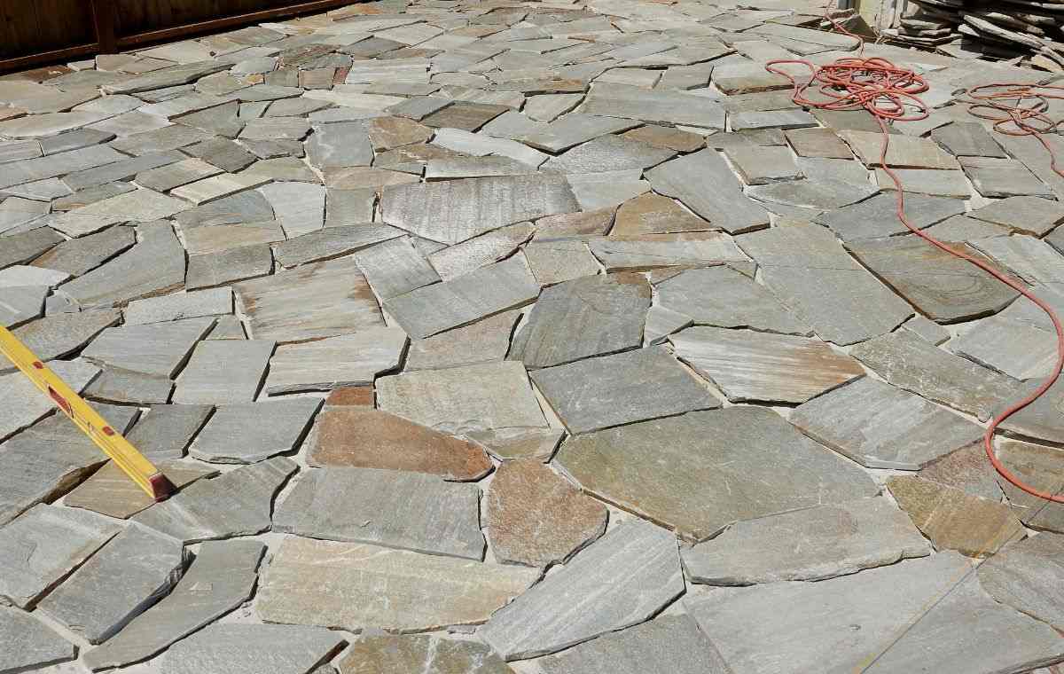 Flagstone patio installation in progress with natural stone layout and leveling tools