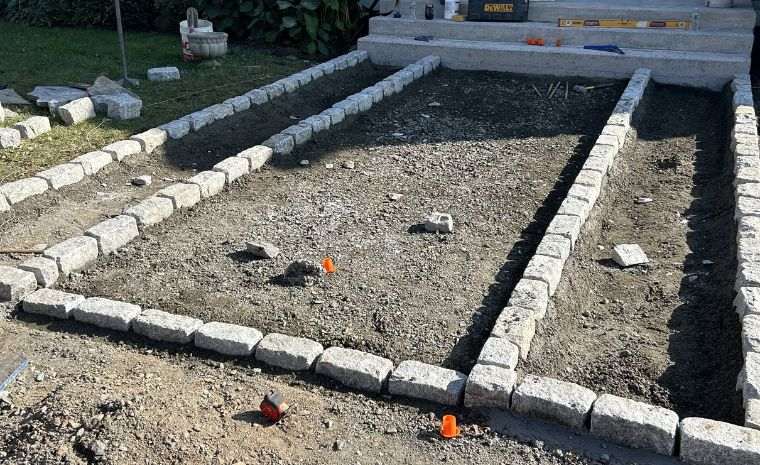 Gravel base prep with stone edging layout for flagstone patio installation