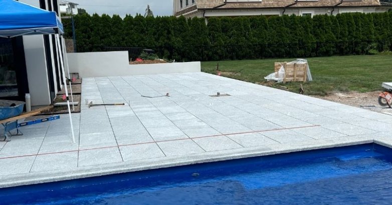 Stone patio installation in progress near pool for durable and stylish outdoor space