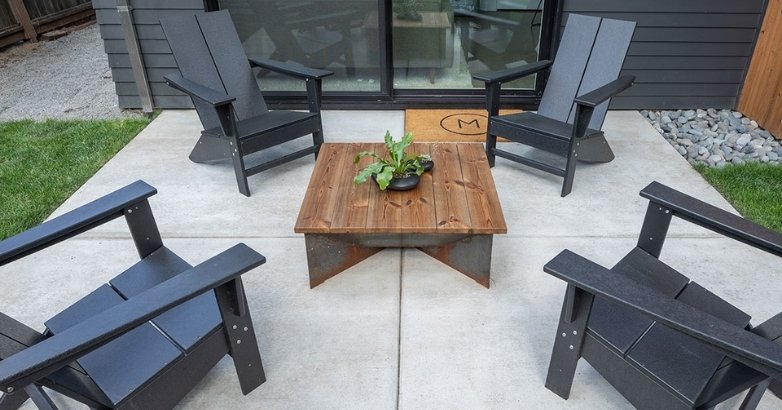 Concrete patio with Adirondack chairs and table for clean, modern outdoor seating space